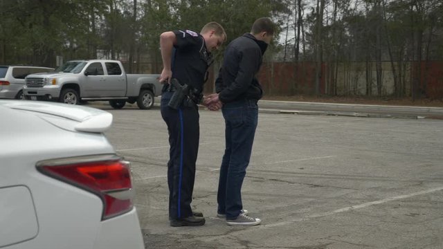 Police officer handcuffs a drunk driver who failed a DUI test during a traffic stop.