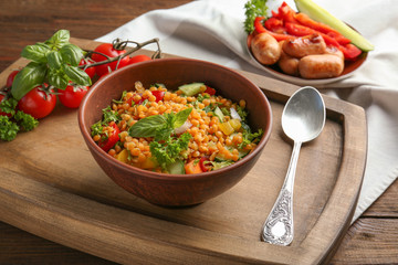 Bowl with delicious lentils salad on wooden board