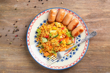 Plate with delicious lentils salad and sausages on wooden table