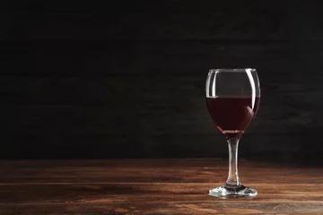 Fotobehang Glass with delicious red wine on table against dark background © New Africa