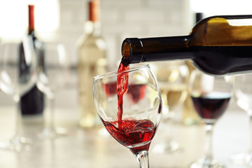 Pouring delicious red wine into glass on table