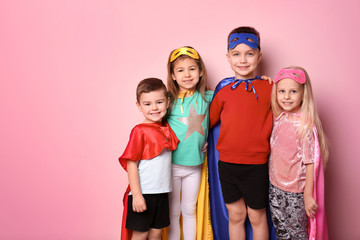 Cute children in superhero costumes on color background