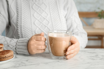 Young woman with delicious hot cocoa drink at table