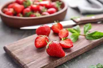Wooden board with ripe red strawberries on table
