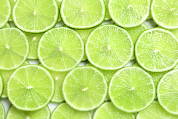 Fototapeta na wymiar Fresh sliced ripe limes as background, top view