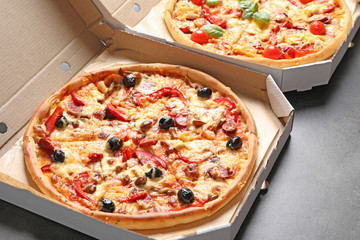 Cardboard box with delicious pizza on table