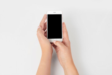 Fototapeta na wymiar Young woman holding mobile phone with blank screen in hands on white background