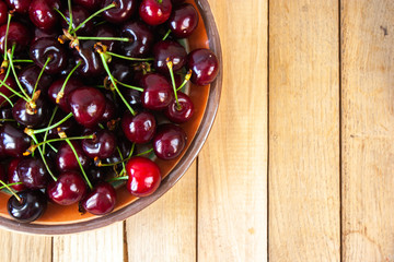 Fresh cherry on plate on wooden background. Sweet cherries.