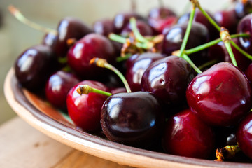 Fresh cherry on plate on wooden background. Sweet cherries.