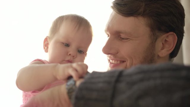 Bearded dad kissing baby. Close up of happy father with child on hands. Baby touching wrist watch on father hand. Father time concept. Dad come back home after work. Daddy kissing child