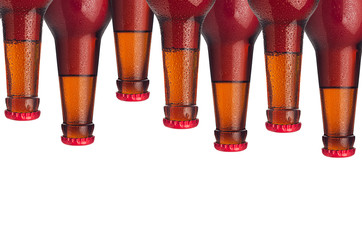 Decorative pattern of sealed lager beer bottles with red ale and water drops isolated on white...