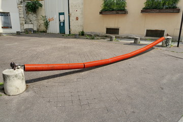 Rue barrée par une chaîne protégée par un tube rouge.