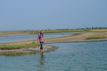 a man in blue jeans and a red shirt walking the river