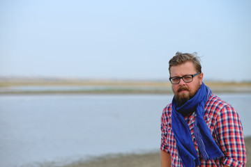 a man in blue jeans and a red shirt walking the river