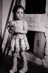 The girl is standing and holding a doll back and white photo
