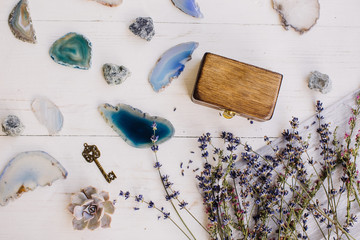 lavender, blue and turquoise stones, key and wooden casket on a white wooden background