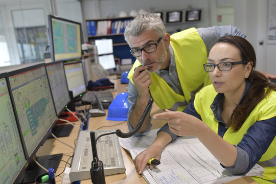 Technicians Working In Industrial Plant Control Room