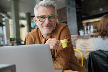 Trendy middle-aged man drinking expresso at coffee shop