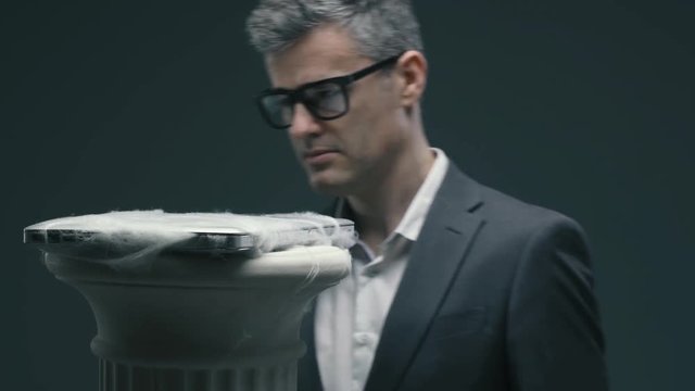 Businessman checking an old laptop covered with dust and cobwebs