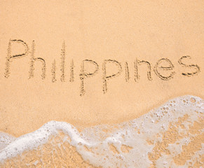 The word Philippines written in the sand on beach