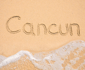 The word Cancun written in the sand on beach