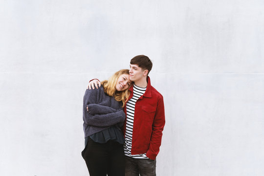 young affectionate couple standing in front of concrete cement wall with copy space