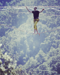 Highliner on a rope. Highline on a background of mountains. Extreme sport on the nature. Balancing on the sling. Equilibrium at altitude.