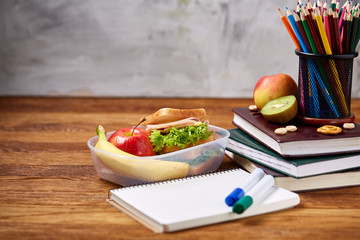 Concept of school lunch break with healthy lunch box and school supplies on wooden desk, selective...