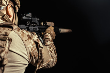 Special forces soldier with rifle on dark background