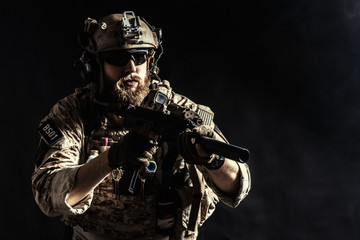 Special forces soldier with rifle on dark background