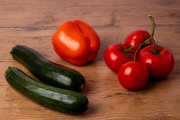 Fresh zucchinis and tomatos on a wooden background