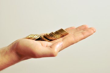 A tall hand of a men holding golden coins in palm, on white background, isolated, side view, copy space