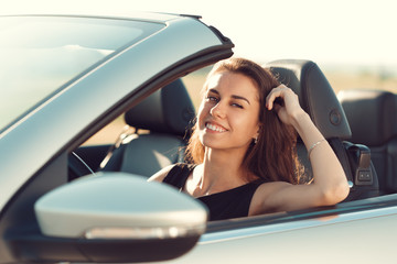 young girl driving cabrio car, on sunset light