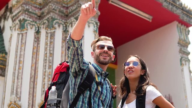 Young interracial couple tourist backpackers at Thai temple during  summer vacations in Bangkok, Thailand