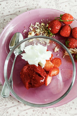 Strawberry granita with whipped cream and fresh strawberries on pink plate. Refreshing hot weather dessert. View from above.