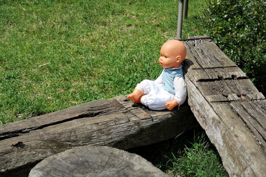 Poup&eacute;e b&eacute;b&eacute; assise sur des madriers de bois au soleil.