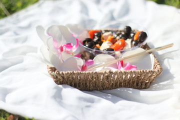 Antipasti in a basket with flowers on grass