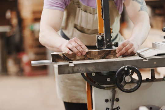 Close up view of hardworking focused professional unrecognizable carpenter man  is standing on electric cutter in the fabric workshop.