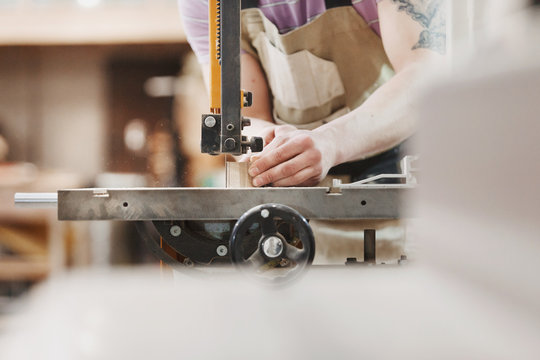 Close up view of hardworking focused professional unrecognizable carpenter man  is standing on electric cutter in the fabric workshop.