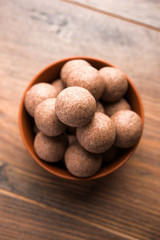 Nachni laddu or Ragi laddoo or balls made using  finger millet, sugar and ghee. It's a healthy food from India. Served in a bowl or plate over moody background. Selective focus