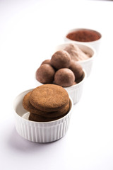 Nachni / Ragi laddu and biscuits or cookies made using  finger millet, sugar and ghee. It's a healthy food from India. Served in a bowl or plate with raw whole and powder. Selective focus