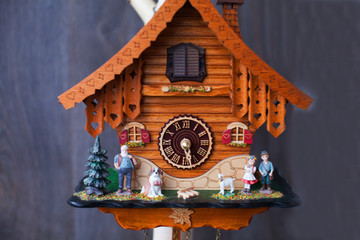 Traditional handmade colorful wooden cuckoo clocks with birds that chime the hour hanging on a wooden wall, one large one smaller