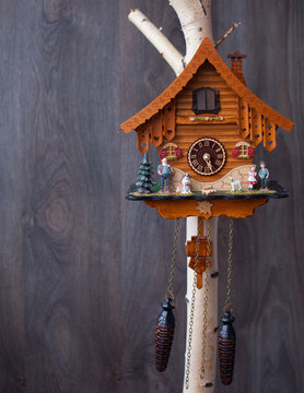 Traditional handmade colorful wooden cuckoo clocks with birds that chime the hour hanging on a wooden wall, one large one smaller