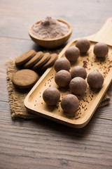 Nachni / Ragi laddu and biscuits or cookies made using  finger millet, sugar and ghee. It's a healthy food from India. Served in a bowl or plate with raw whole and powder. Selective focus