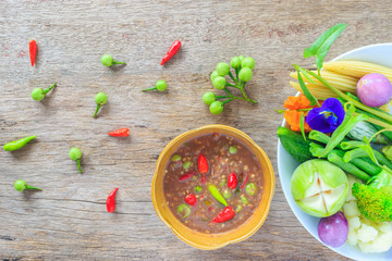 Shrimp paste sauce and vegetable on white dish with wooden background.