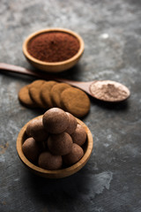 Nachni / Ragi laddu and biscuits or cookies made using  finger millet, sugar and ghee. It's a healthy food from India. Served in a bowl or plate with raw whole and powder. Selective focus