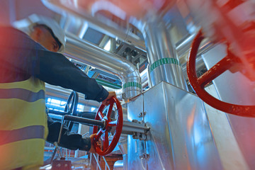 industrial factory worker turning red wheel of valve