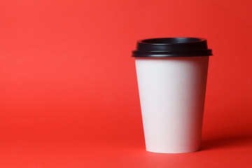 Paper coffee container with black lid on red background. Takeaway drink container. Template of drink cup for your design. Can put text, image, and logo.