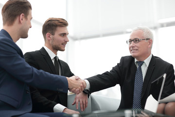 Partners concluding deal and shaking hands in the presence of team members