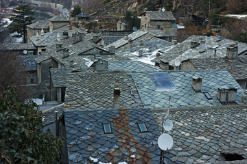 view of the stone roofs of an alpine village in winter.